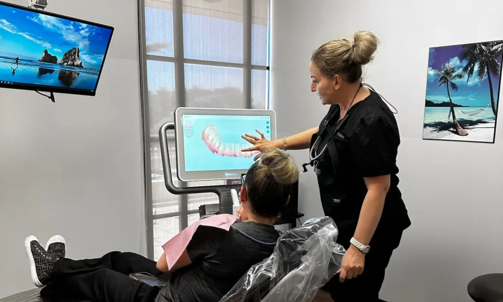 Woman instructing man in dental virtual reality training simulation in modern clinic setting.