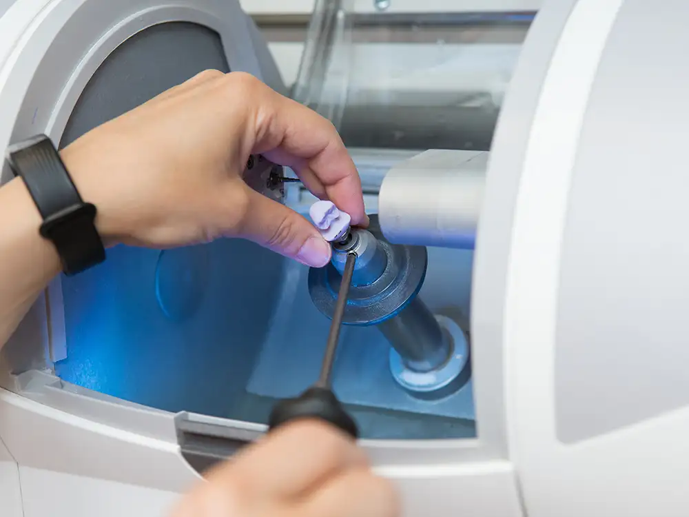 Hand inserting blue liquid detergent pod into washing machine drum.